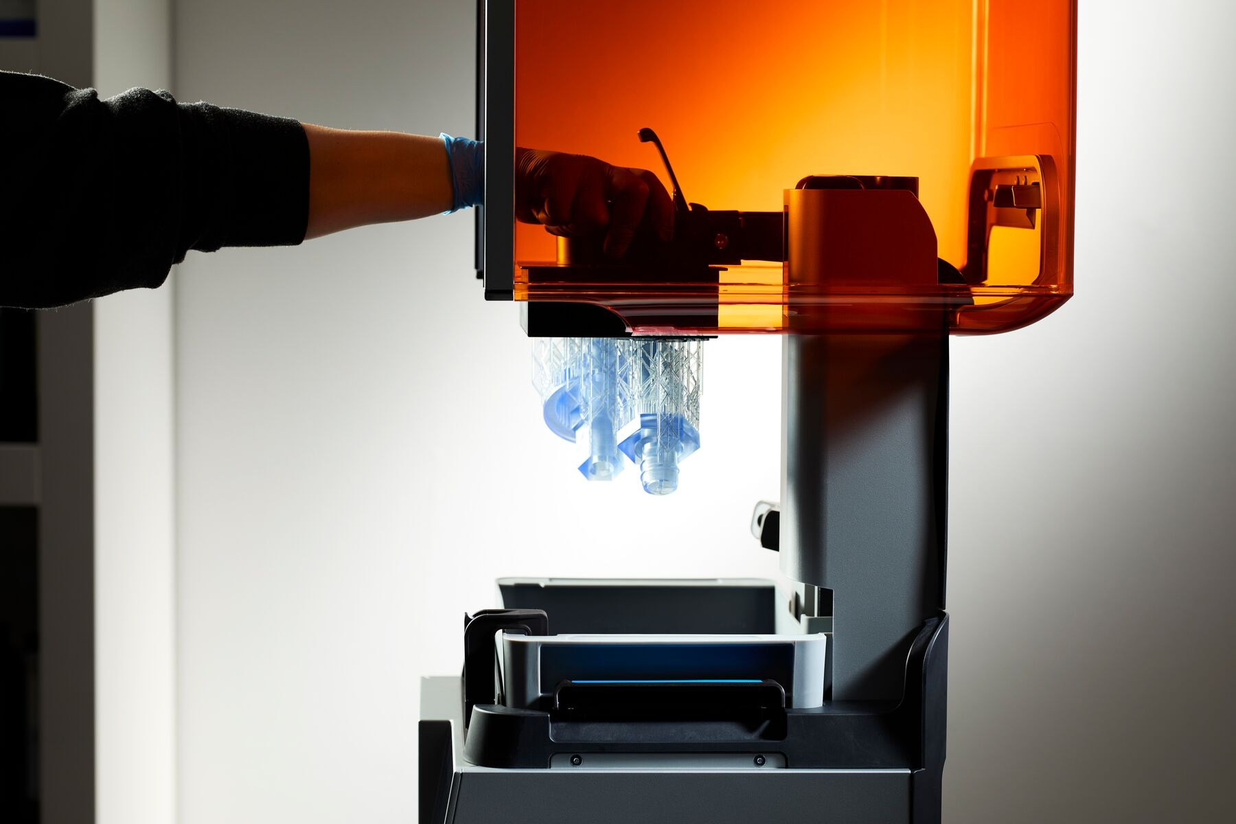 Resin 3D printer with freshly printed parts being removed from the build platform